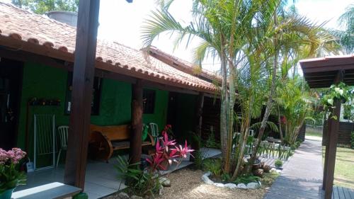 una casa verde con palme di fronte di Hospedaria aconchego 5 a Garopaba