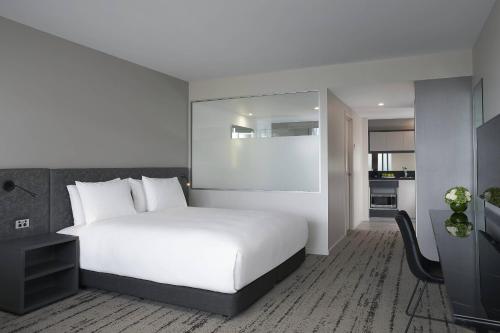a bedroom with a large white bed and a desk at Courtyard by Marriott Brisbane South Bank in Brisbane