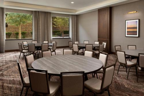 a conference room with tables and chairs and windows at The Otis Hotel Austin, Autograph Collection in Austin