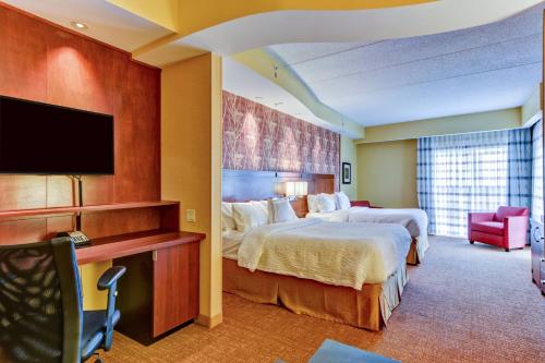 a hotel room with two beds and a flat screen tv at Courtyard by Marriott Bridgeport Clarksburg in Bridgeport