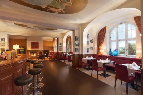 a restaurant with tables and chairs and a bar at Falkenstein Grand, Autograph Collection in Königstein im Taunus