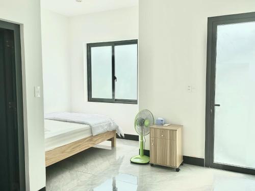 a bedroom with a bed and a fan and a window at Nhà Nghĩ Bà Rịa - Bình An in Ấp Nam