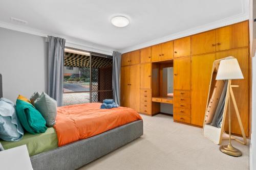 ein Schlafzimmer mit einem orangenen Bett und einem Fenster in der Unterkunft Cozy Lake Escape near Parliament, Embassies, Golf Club in Yarralumla