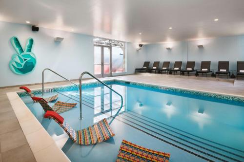 a swimming pool with chairs and a swimming pool at Aloft Atlanta Perimeter Center in Sandy Springs