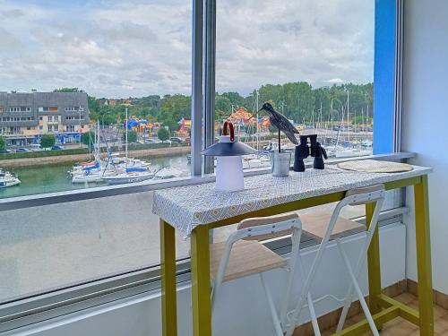 une table avec deux chaises devant une fenêtre dans l'établissement Charmant Studio à Courseulles-sur-Mer avec Wifi et Parking - FR-1-746-27, à Courseulles-sur-Mer