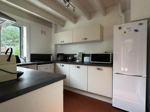 une cuisine avec des armoires blanches et un réfrigérateur blanc dans l'établissement Villa 4 Pièces, 3 Chambres, Animaux Acceptés, Parking, WiFi, Proche Mer - FR-1-705-92, aux Mathes