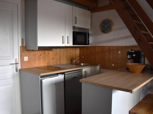 une cuisine avec des armoires blanches et un comptoir en bois dans l'établissement Confortable Appartement 2 pièces en mezzanine avec jardin à Bolquère - FR-1-592-80, à Font-Romeu-Odeillo-Via