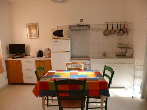 une cuisine avec une table avec des chaises et un réfrigérateur dans l'établissement T2 Confortable - Près Centre-Ville avec Parking - FR-1-571-71, à Balaruc-les-Bains
