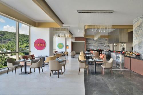 a restaurant with tables and chairs and a kitchen at Courtyard by Marriott Navi Mumbai in Navi Mumbai