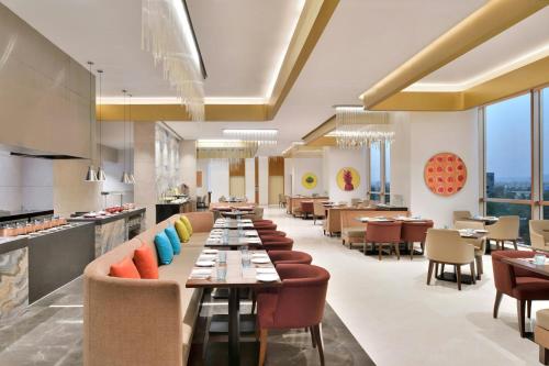 a restaurant with long tables and chairs and windows at Courtyard by Marriott Navi Mumbai in Navi Mumbai