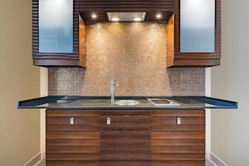 a kitchen with a sink and wooden cabinets at Qabila Westbay Hotel in Doha