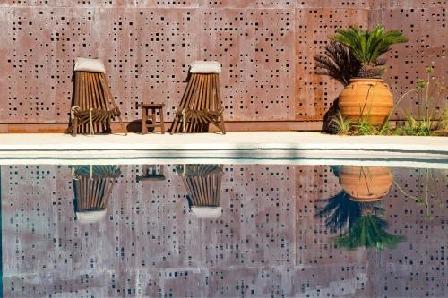a pool of water with three plants in front of a wall at Domes of Corfu, Autograph Collection in Glyfada