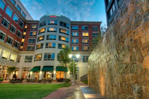a building with a stone wall in front of it at Courtyard by Marriott Greenville Downtown in Greenville
