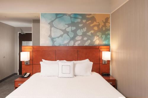 a bedroom with a bed with white pillows and a painting at Courtyard by Marriott Greenville Downtown in Greenville
