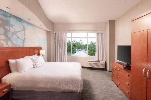 a hotel room with a bed and a television at Courtyard by Marriott Greenville Downtown in Greenville