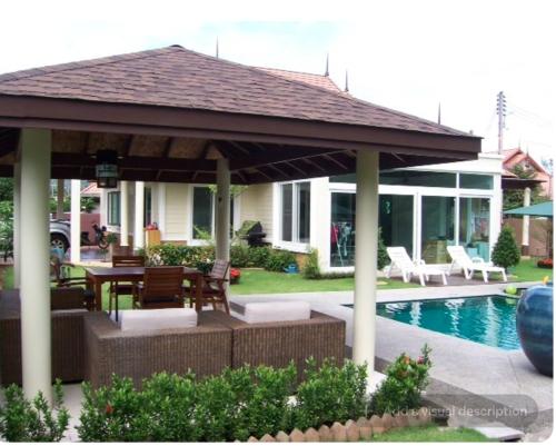 a pavilion with a table and chairs next to a pool at Pool Villa in Thalang in Ban Na Nai