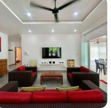 a living room with a red couch and a tv at Pool Villa in Thalang in Ban Na Nai
