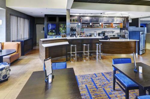 a restaurant with a bar with blue chairs and tables at Courtyard Chicago Glenview/Northbrook in Glenview