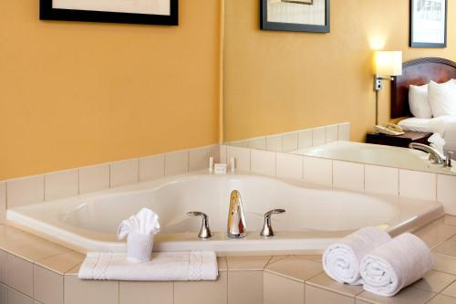 a bathroom with a tub and a sink with towels at Courtyard Hartford Manchester in Manchester