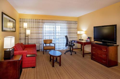 a hotel room with a living area with a large television at Courtyard Hartford Manchester in Manchester