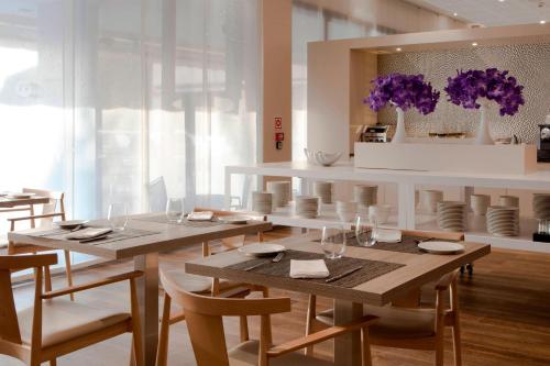 a dining room with wooden tables and chairs and purple flowers at AC Hotel San Cugat by Marriott in Sant Cugat del Vallès