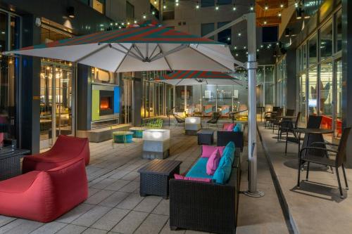 a patio with chairs and tables and an umbrella at aloft Green Bay in Green Bay