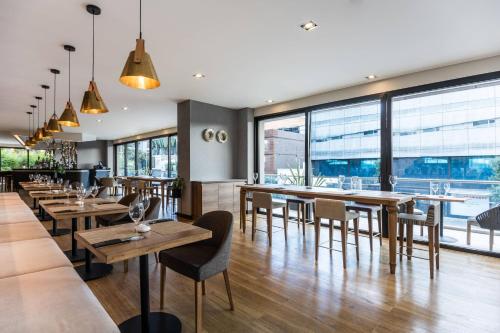 a restaurant with wooden tables and chairs and large windows at AC Hotel by Marriott Bogota Zona T in Bogotá