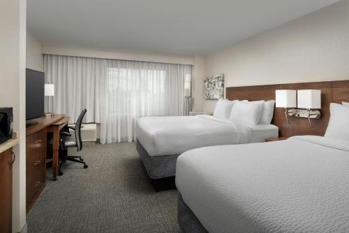 a hotel room with two beds and a desk and a television at Courtyard Chico in Chico