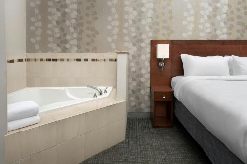 a hotel room with a bed and a tub next to a bed at Courtyard Chico in Chico