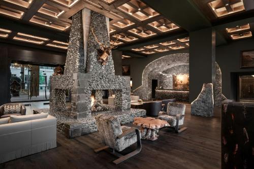 a living room with a stone fireplace and chairs at Grand Bohemian Lodge Greenville, Autograph Collection in Greenville