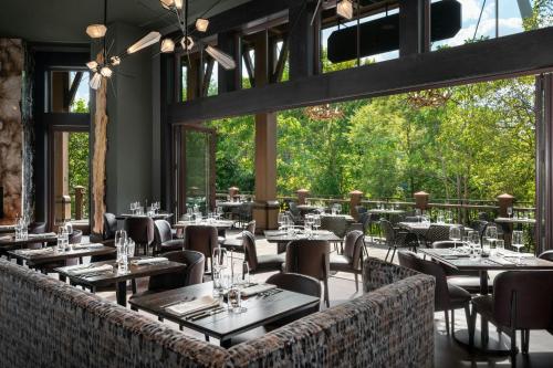 a restaurant with tables and chairs and large windows at Grand Bohemian Lodge Greenville, Autograph Collection in Greenville