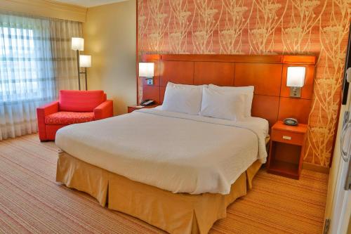a hotel room with a large bed and a red chair at Courtyard Biloxi North/D'Iberville in Biloxi
