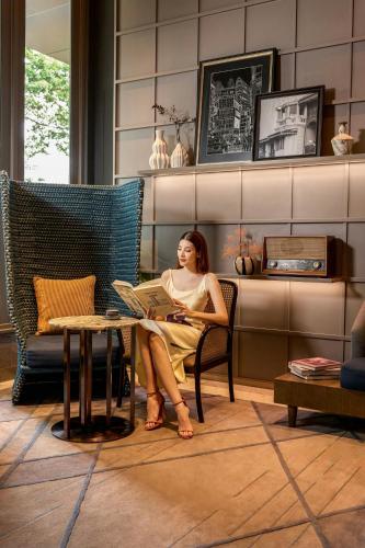 a woman sitting at a table with a laptop at Madi Paidi Bangkok, Autograph Collection in Bangkok