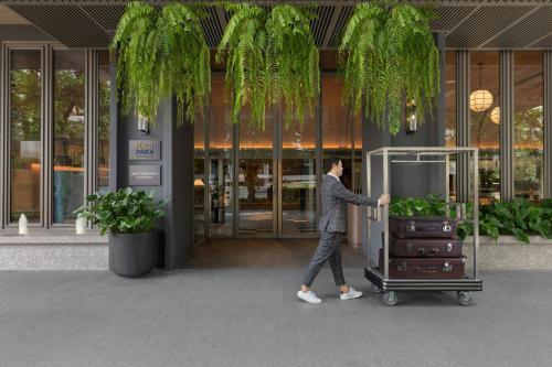 a man pushing a cart in front of a building at Madi Paidi Bangkok, Autograph Collection in Bangkok