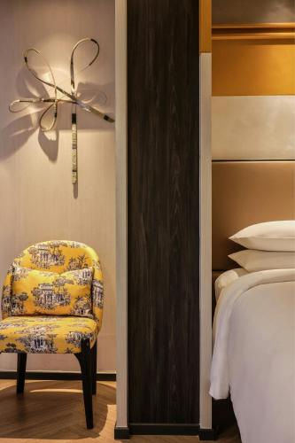 a bedroom with a chair next to a bed at Madi Paidi Bangkok, Autograph Collection in Bangkok