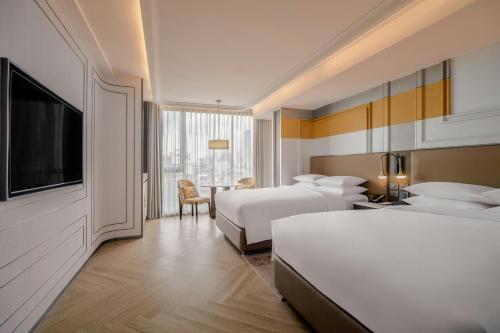 a hotel room with two beds and a flat screen tv at Madi Paidi Bangkok, Autograph Collection in Bangkok
