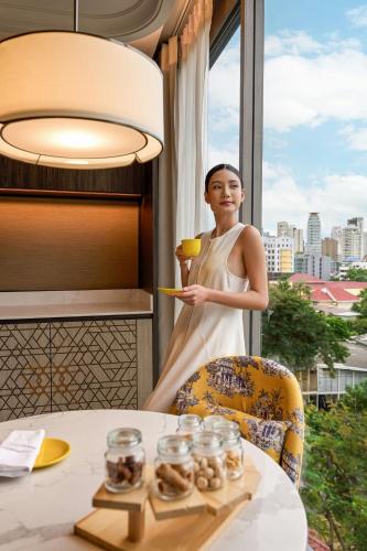 a woman holding a glass of wine in front of a table at Madi Paidi Bangkok, Autograph Collection in Bangkok
