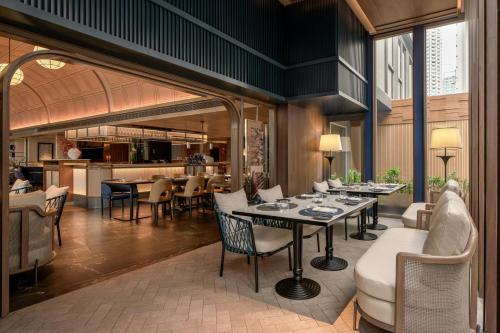 a restaurant with tables and chairs and a kitchen at Madi Paidi Bangkok, Autograph Collection in Bangkok