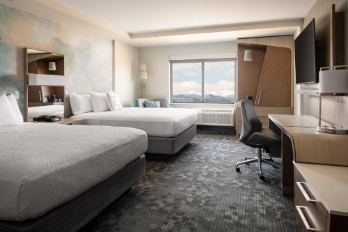 a hotel room with two beds and a desk at Courtyard by Marriott Loveland Fort Collins in Loveland