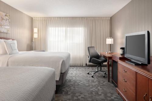 a hotel room with two beds and a desk with a television at Courtyard Chicago Bloomingdale in Bloomingdale
