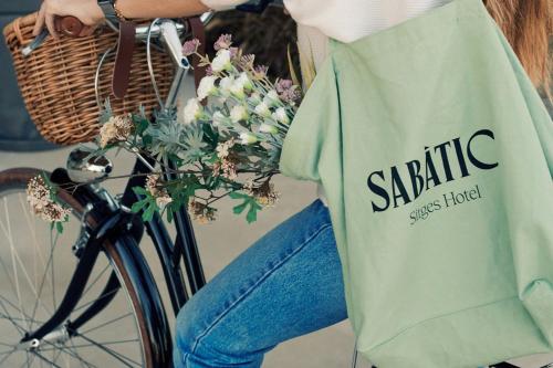 a person riding a bike with a bag and flowers at Sabàtic Sitges Hotel, Autograph Collection in Sitges