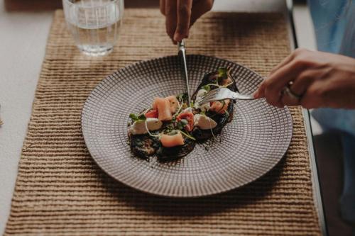 a person eating a plate of food on a table at Sabàtic Sitges Hotel, Autograph Collection in Sitges
