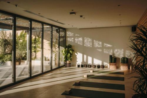 a lobby with large windows and stairs in a building at Sabàtic Sitges Hotel, Autograph Collection in Sitges
