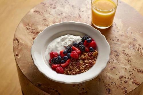 a bowl of cereal with berries and a glass of orange juice at Viewline Resort Snowmass, Autograph Collection in Snowmass Village