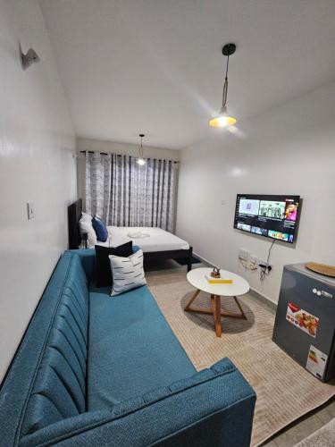 a living room with a blue couch and a tv at Happy Stay homes in Ongata Rongai 