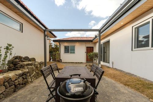 a patio with a table and chairs and a building at Jeju Stone Courtyard Pension in Jeju