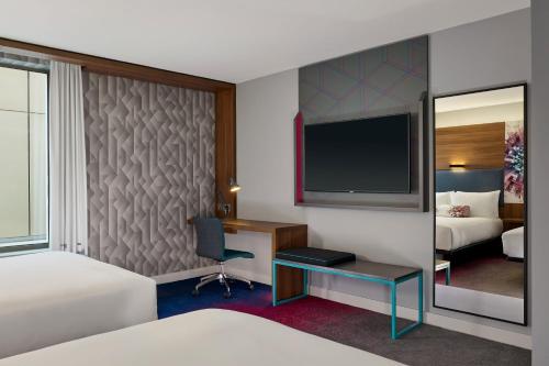 a hotel room with a bed and a desk and a tv at Aloft Birmingham Eastside in Birmingham