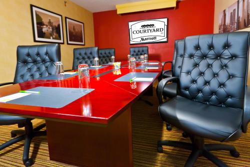 a conference room with a red table and chairs at Courtyard Chicago O'Hare in Des Plaines