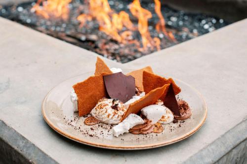 two desserts on a plate next to a fire at The Stella Hotel, Autograph Collection in Bryan