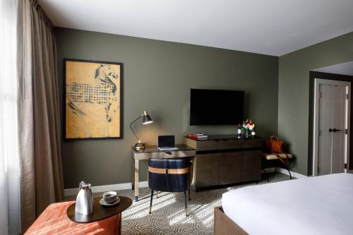 a hotel room with a bed and a desk with a television at Hotel Vin, Autograph Collection in Grapevine